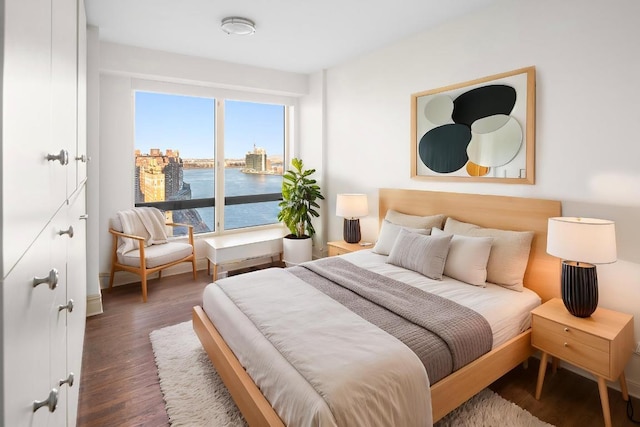 bedroom featuring a water view and dark hardwood / wood-style floors