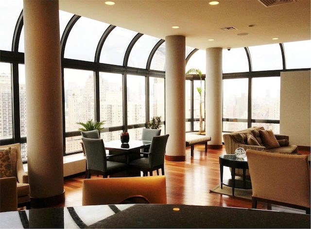 interior space featuring visible vents, a city view, expansive windows, wood finished floors, and recessed lighting