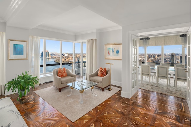 sitting room with a healthy amount of sunlight, baseboards, a water view, and ornamental molding