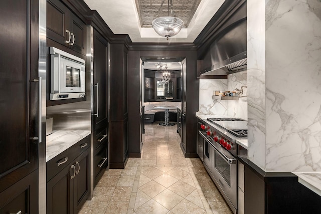 kitchen featuring decorative backsplash, a tray ceiling, double oven range, wall chimney range hood, and built in microwave