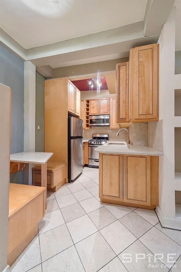 229 E 28th St Unit Lh, New York City, NY 10016 - kitchen with appliances with stainless steel finishes, light countertops, backsplash, a peninsula, and light brown cabinets