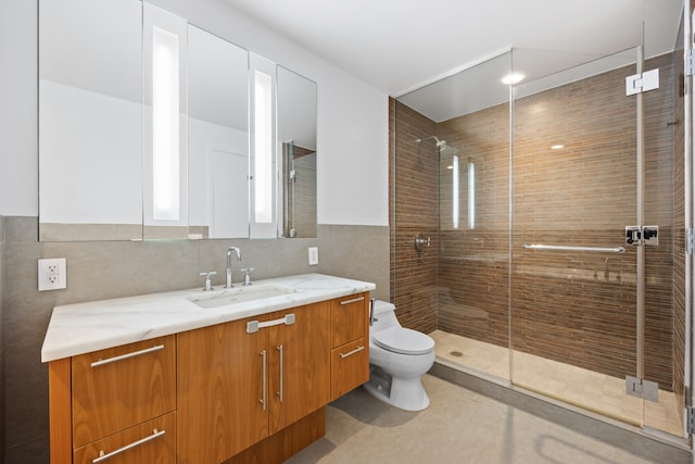 bathroom featuring vanity, a shower stall, toilet, and tile walls