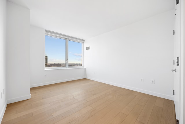 spare room with visible vents, baseboards, and light wood-style floors