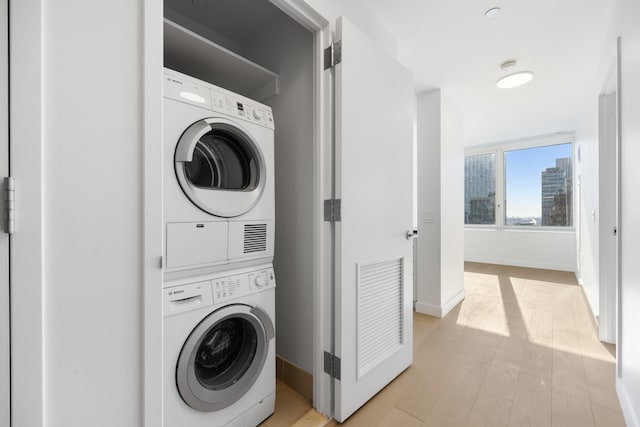 washroom with visible vents, baseboards, laundry area, light wood-style floors, and stacked washer / dryer