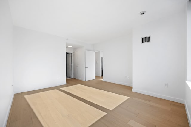 unfurnished room featuring light wood finished floors, visible vents, and baseboards