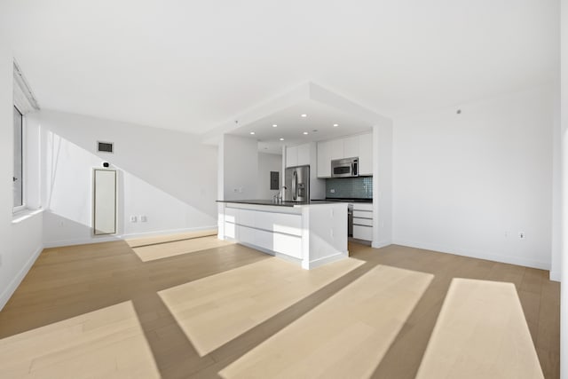 unfurnished living room featuring visible vents, recessed lighting, baseboards, and light wood-style floors