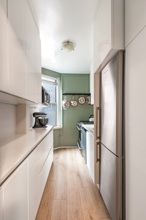 kitchen with white cabinetry, appliances with stainless steel finishes, and light hardwood / wood-style flooring