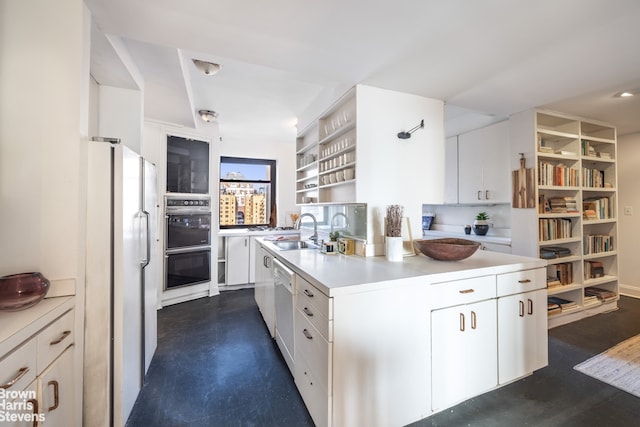 kitchen with a center island with sink, light countertops, freestanding refrigerator, white cabinets, and a sink