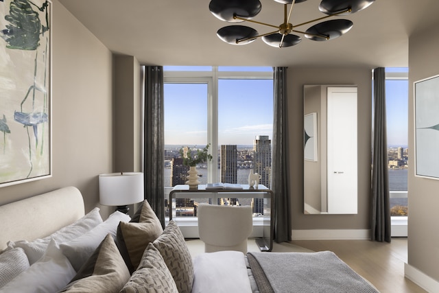 bedroom featuring a city view, wood finished floors, baseboards, and an inviting chandelier