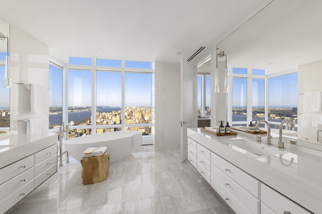 bathroom with floor to ceiling windows, a water view, vanity, and a bathtub