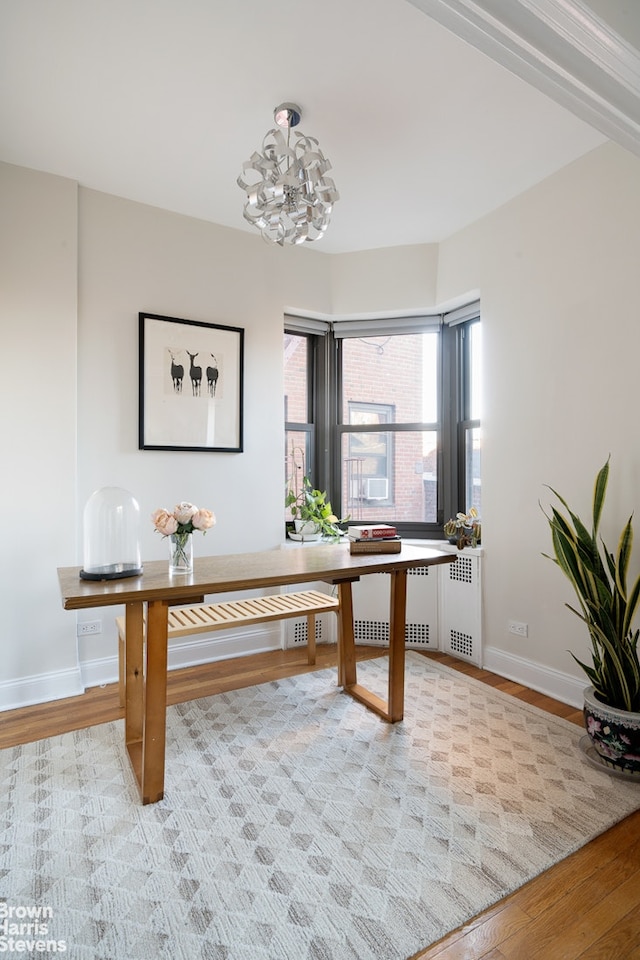 office area with baseboards, light wood-style floors, and an inviting chandelier