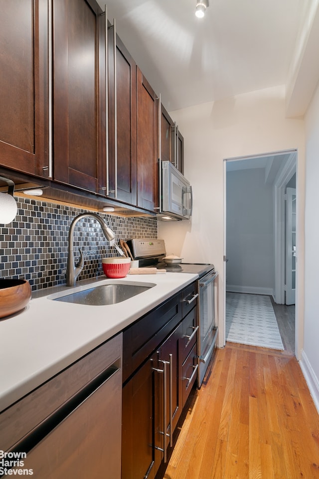 kitchen with tasteful backsplash, light countertops, light wood-style floors, stainless steel appliances, and a sink