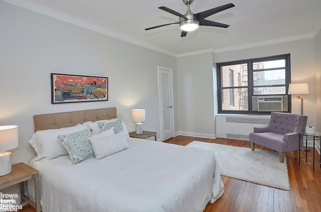 bedroom featuring hardwood / wood-style flooring, ceiling fan, ornamental molding, and radiator