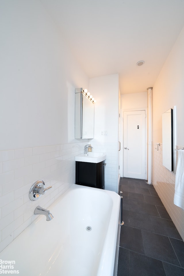 full bath with vanity, tile patterned flooring, wainscoting, tile walls, and a bath