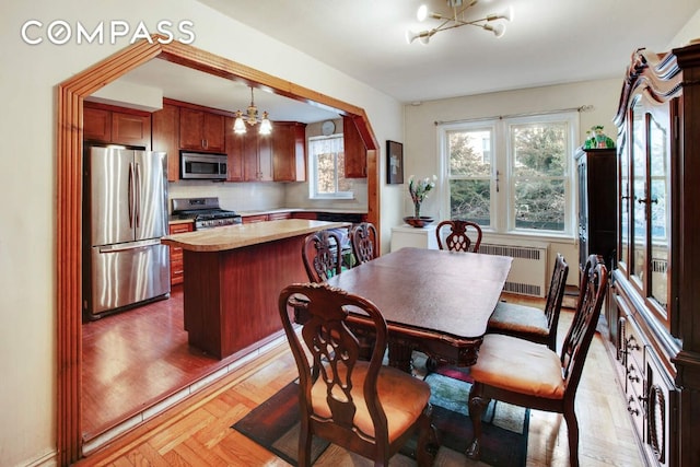 dining room with radiator, a chandelier, and light parquet floors