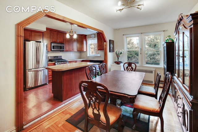 dining area featuring parquet floors, a notable chandelier, and radiator heating unit