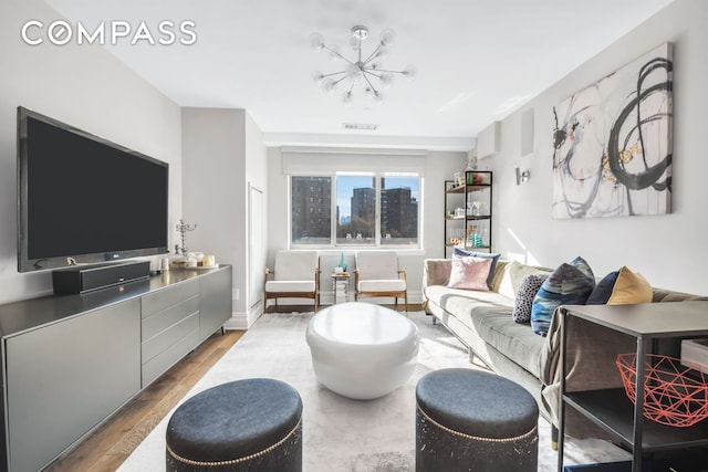 living area with visible vents, baseboards, a notable chandelier, and wood finished floors