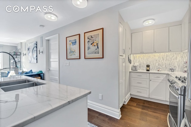 kitchen featuring a sink, white cabinetry, light stone countertops, stainless steel gas stove, and dark wood finished floors