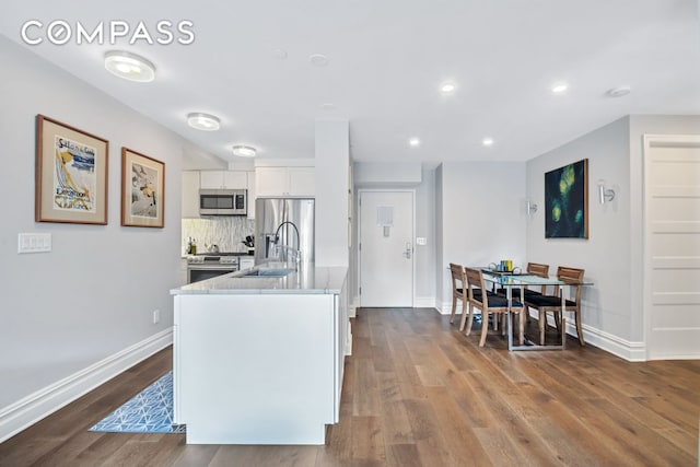 kitchen with dark wood finished floors, white cabinets, stainless steel appliances, and a sink