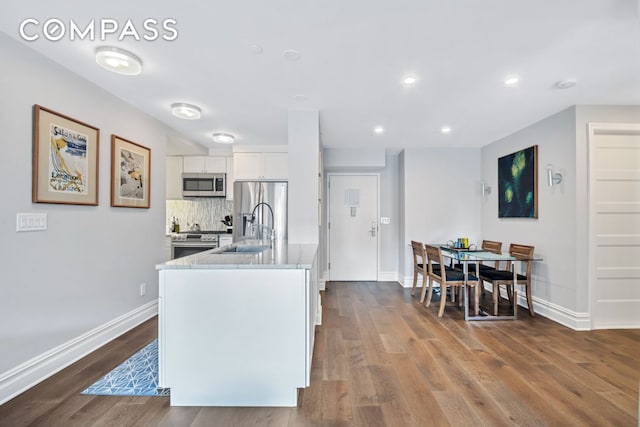1400 5th Ave Unit 6K, New York City, NY 10026 - kitchen with stainless steel appliances, a sink, white cabinetry, dark wood-type flooring, and backsplash