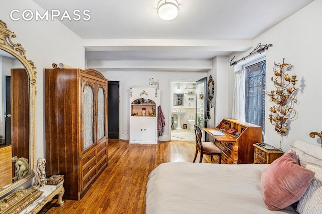 bedroom featuring beamed ceiling, connected bathroom, and dark hardwood / wood-style flooring