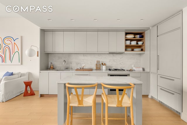 kitchen with light countertops, light wood finished floors, modern cabinets, and a sink