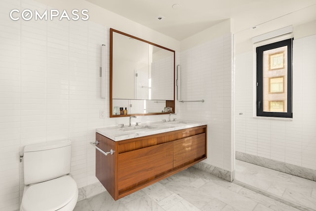 full bath with a sink, tile walls, marble finish floor, and toilet