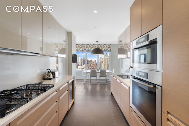 kitchen featuring stainless steel appliances, light countertops, wine cooler, dark tile patterned floors, and modern cabinets