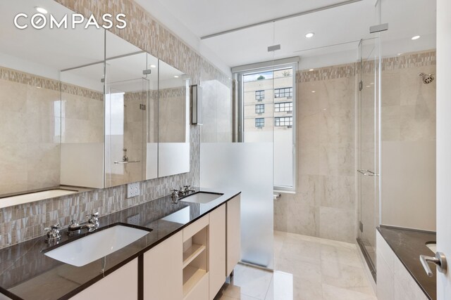 full bath with double vanity, a stall shower, tile walls, and a sink