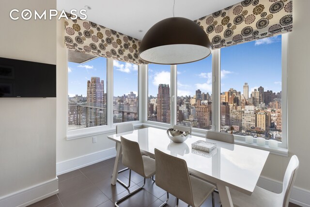 dining room featuring a wealth of natural light, a view of city, dark tile patterned flooring, and baseboards