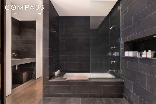 bathroom with tiled shower / bath combo, tile walls, and wood finished floors