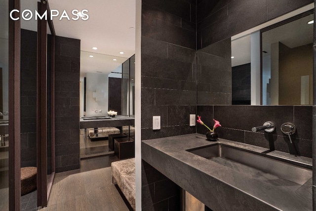 bathroom with tile walls, sink, backsplash, and wood-type flooring