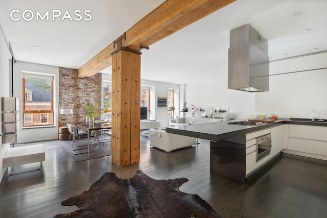 kitchen with dark wood-style flooring, dark countertops, wall oven, beam ceiling, and open floor plan
