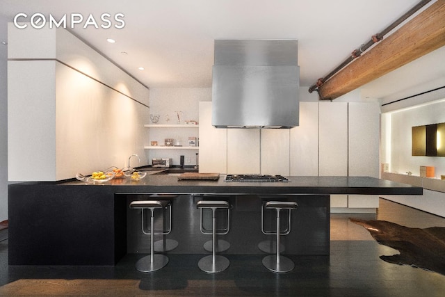 kitchen featuring beam ceiling, island range hood, and stainless steel gas stovetop