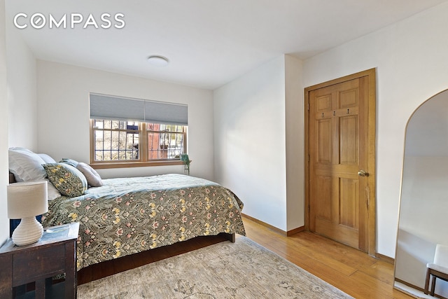 bedroom with wood finished floors, baseboards, and arched walkways