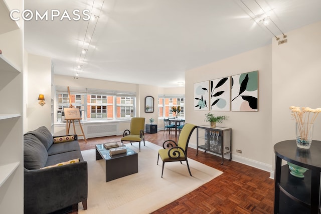 living area with baseboards, rail lighting, and radiator heating unit