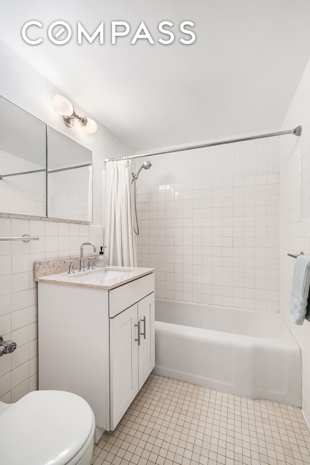 full bath with tile patterned flooring, tile walls, toilet, shower / tub combo with curtain, and vanity