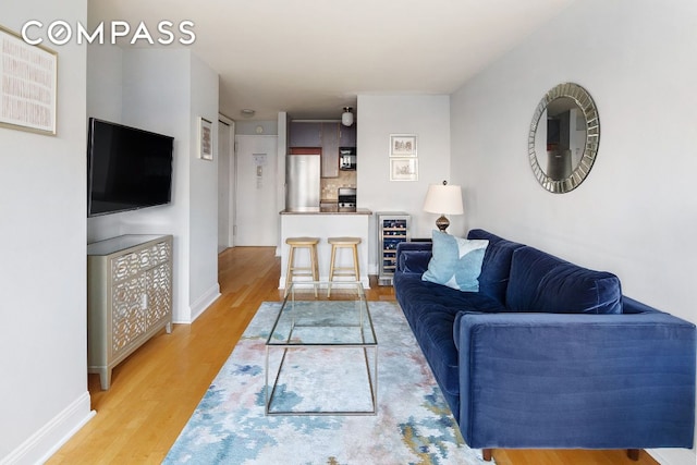 living area featuring light wood-style floors, wine cooler, and baseboards