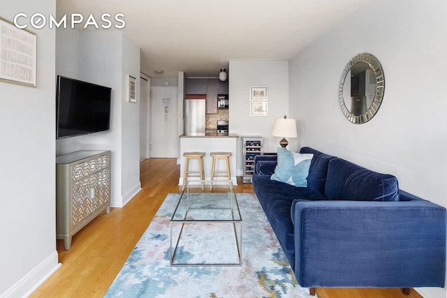 living area featuring wine cooler, baseboards, and wood finished floors