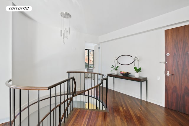 interior space featuring baseboards, visible vents, dark wood-type flooring, and an upstairs landing