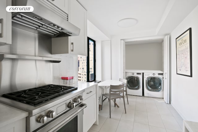 211 Madison Ave Unit 16B, New York City, NY 10016 - kitchen featuring stainless steel stove, washer and dryer, light countertops, under cabinet range hood, and white cabinets