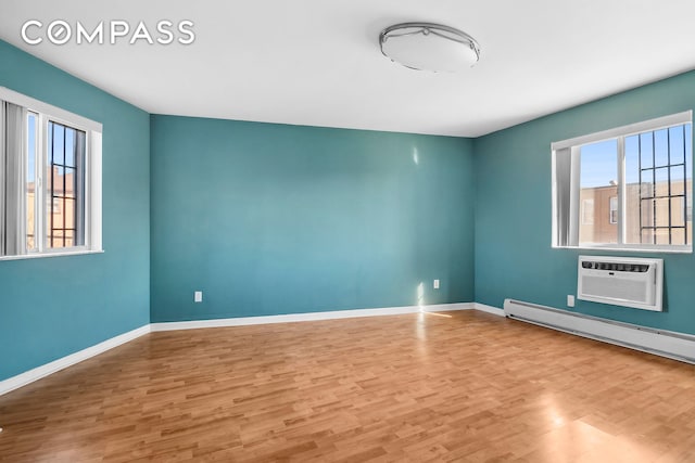 unfurnished room featuring a wall unit AC, plenty of natural light, and light wood-style flooring