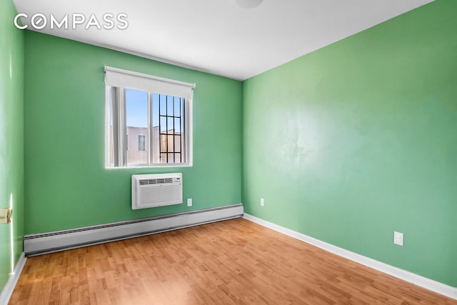 unfurnished room featuring light wood-style flooring, baseboards, baseboard heating, and a wall mounted AC