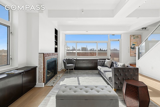 living room with a glass covered fireplace, plenty of natural light, wood finished floors, and stairs