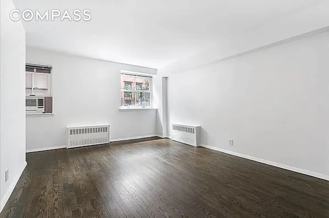 unfurnished room featuring cooling unit, dark wood-type flooring, and radiator heating unit