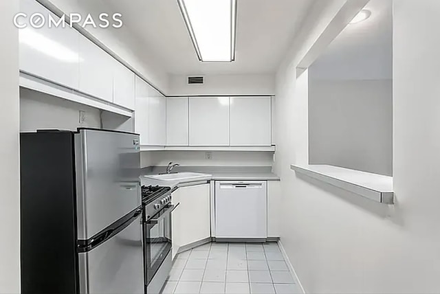 kitchen featuring light tile patterned floors, stainless steel appliances, sink, and white cabinets