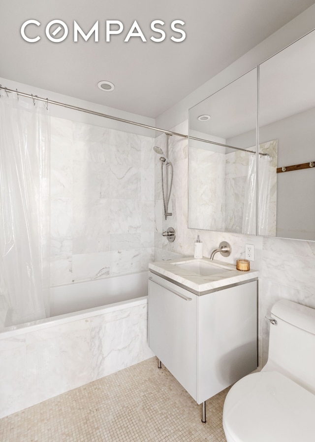 bathroom featuring tiled shower / bath, tile walls, toilet, and vanity