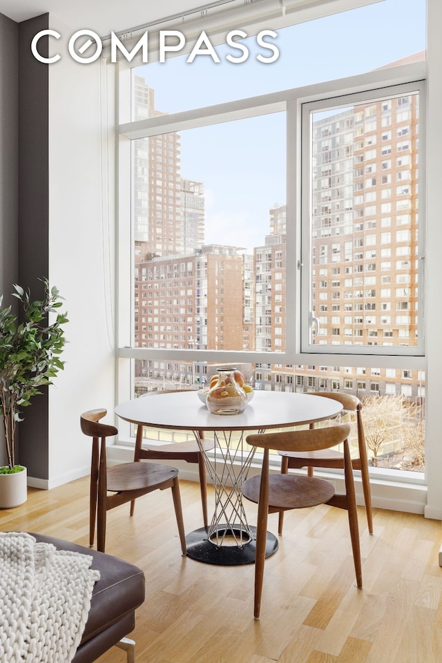 dining room featuring breakfast area, a view of city, baseboards, and wood finished floors