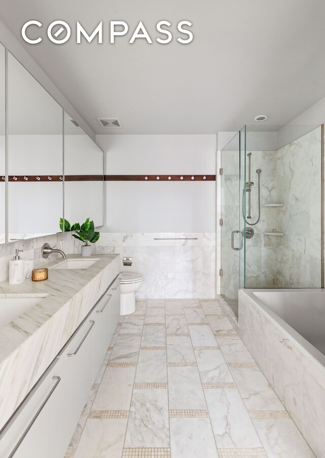 bathroom with visible vents, toilet, a bath, a shower stall, and a sink