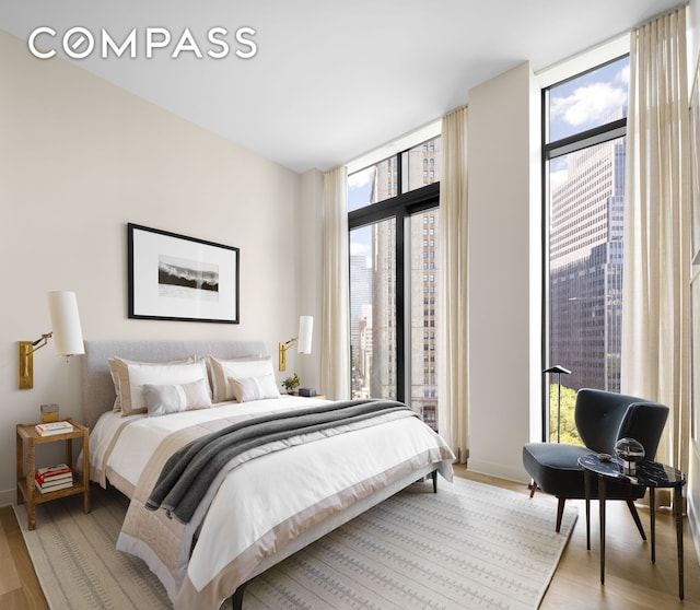 bedroom featuring light wood finished floors, access to outside, multiple windows, and a wall of windows